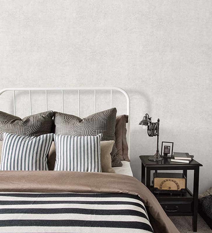 Light grey plaster texture wallcovering in a bedrrom with patterned and striped pillows.

18 Mar 2015 --- Striped and patterned pillows and blanket on bed --- Image by © Hero Images/Corbis